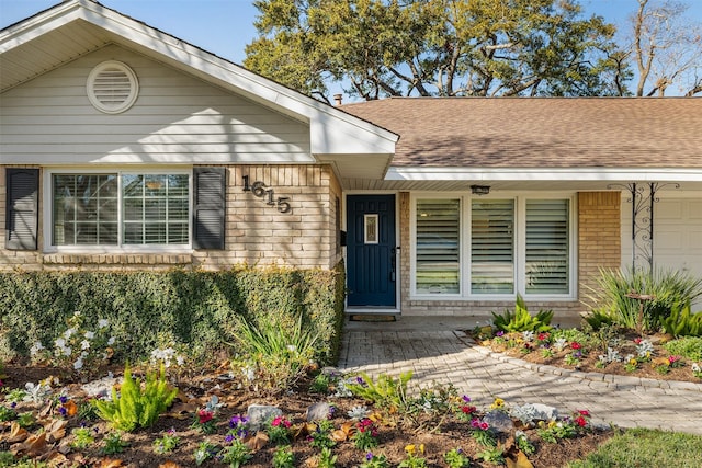 1615 Shadow Bend Dr, Houston, TX 77043 - doorway to property featuring brick siding, roof with shingles, covered porch, and a garage