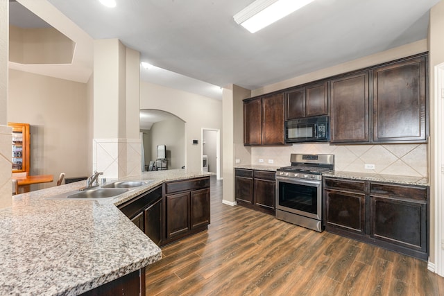 26511 Green Heron, Katy, TX 77494 - kitchen with black microwave, stainless steel gas range, a sink, arched walkways, and dark wood-style floors