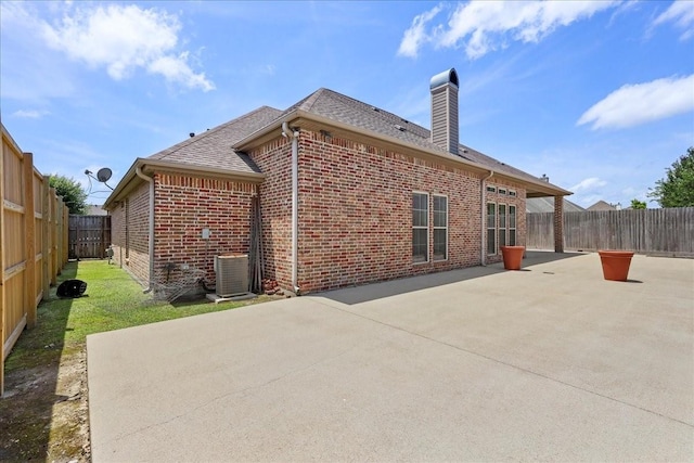 3490 Prescott Dr, Beaumont, TX 77706 - back of property featuring brick siding, a patio area, a chimney, a shingled roof, and central air condition unit
