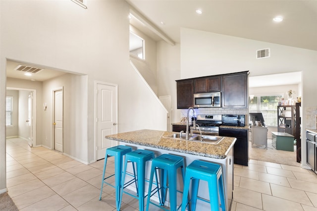 2910 High Garden Ln, Fresno, TX 77545 - kitchen with appliances with stainless steel finishes, a sink, a kitchen island with sink, light tile patterned floors, and a high ceiling