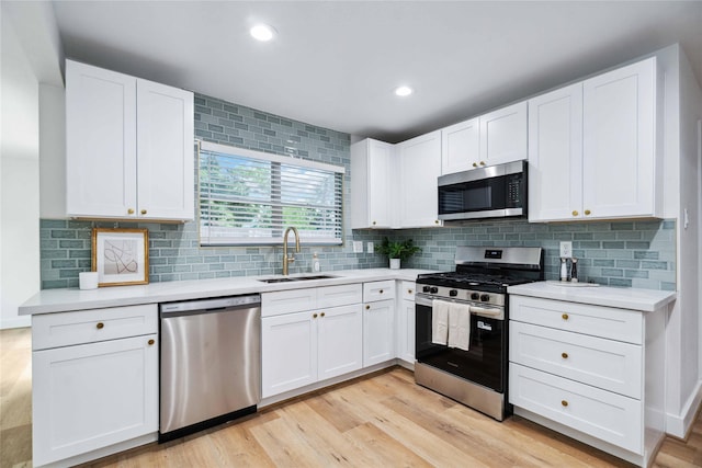 6019 Westover St, Houston, TX 77033 - kitchen featuring stainless steel appliances, a sink, white cabinetry, light countertops, and recessed lighting