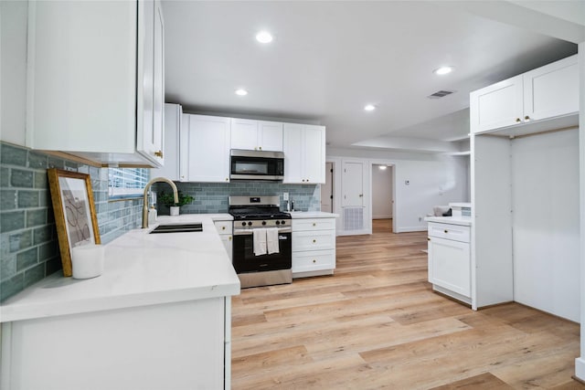 6019 Westover St, Houston, TX 77033 - kitchen featuring stainless steel appliances, a sink, white cabinets, tasteful backsplash, and recessed lighting