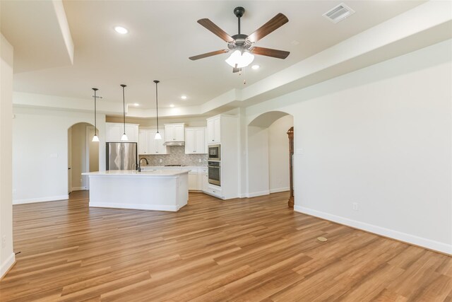 5746 Bobwhite Trl, Manvel, TX 77578 - kitchen with arched walkways, stainless steel appliances, open floor plan, light countertops, and recessed lighting