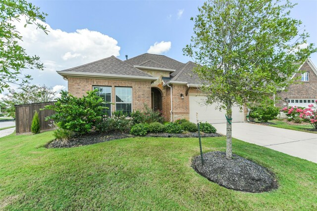 5746 Bobwhite Trl, Manvel, TX 77578 - view of front facade with concrete driveway, brick siding, a garage, a front lawn, and roof with shingles