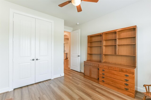 5746 Bobwhite Trl, Manvel, TX 77578 - unfurnished bedroom with arched walkways, light wood-style flooring, a closet, baseboards, and a ceiling fan