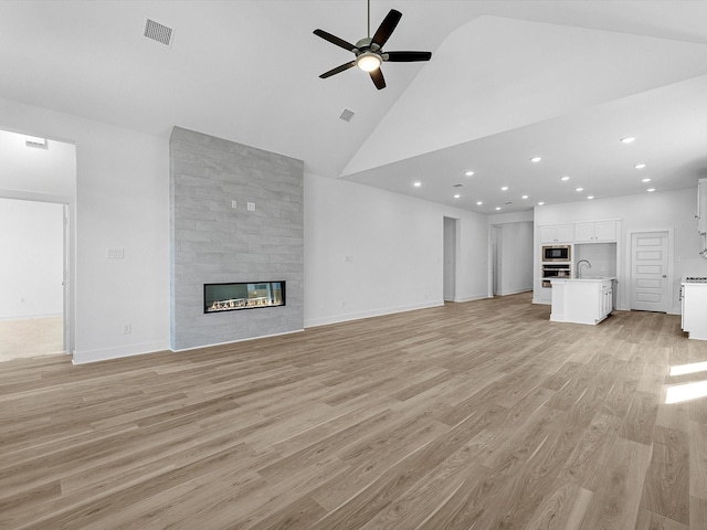 14674 Hereford Grove Ln, Montgomery, TX 77316 - unfurnished living room featuring a sink, ceiling fan, high vaulted ceiling, light wood-type flooring, and a large fireplace