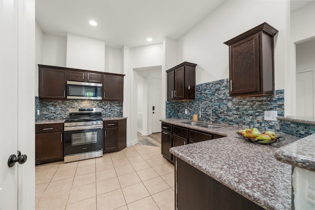 5106 Hardy St, Houston, TX 77009 - kitchen featuring appliances with stainless steel finishes, a sink, dark brown cabinets, decorative backsplash, and light tile patterned floors