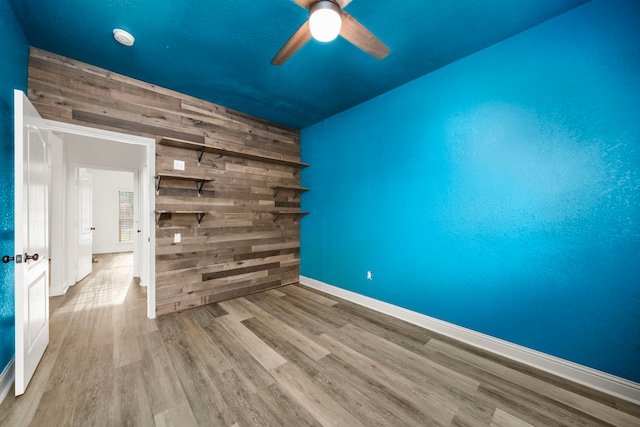 5106 Hardy St, Houston, TX 77009 - spare room featuring wood finished floors, a ceiling fan, baseboards, wooden walls, and a smoke detector