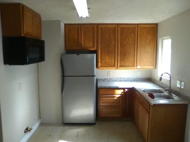 4102 Red Haw Ln, Houston, TX 77022 - kitchen featuring freestanding refrigerator, black microwave, a sink, brown cabinets, and light countertops