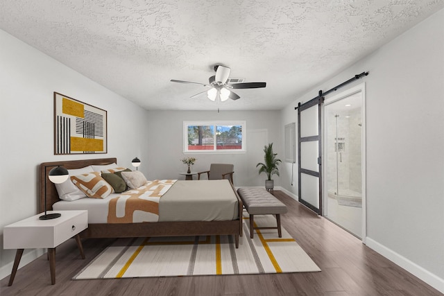 2407 Rambling Brook Dr, Spring, TX 77373 - bedroom featuring wood finished floors, a barn door, baseboards, a textured ceiling, and a ceiling fan