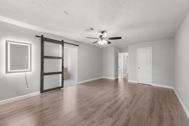 2407 Rambling Brook Dr, Spring, TX 77373 - empty room with a barn door, a textured ceiling, ceiling fan, wood finished floors, and baseboards