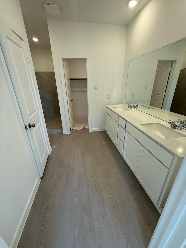 10300 Woodhill Spa Ln, Cleveland, TX 77327 - full bath featuring wood finished floors, double vanity, a spacious closet, tiled shower, and baseboards