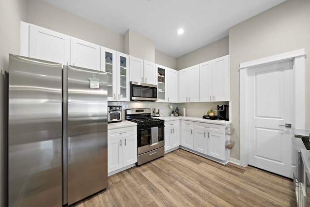 413 Stonework Oaks Ln, Houston, TX 77076 - kitchen with appliances with stainless steel finishes, light wood-type flooring, white cabinets, light countertops, and recessed lighting