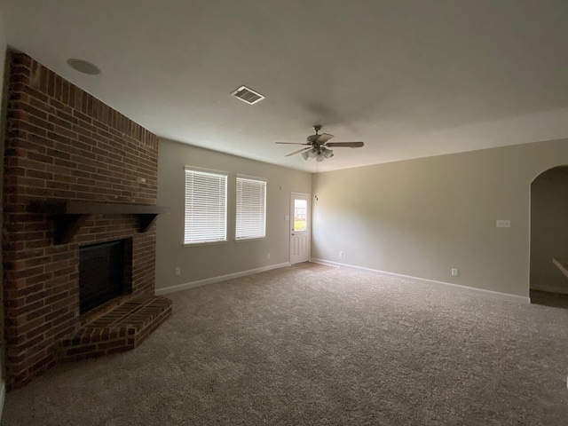 3603 Morgans Cove Ct, Katy, TX 77494 - unfurnished living room with a ceiling fan, carpet flooring, arched walkways, baseboards, and a brick fireplace