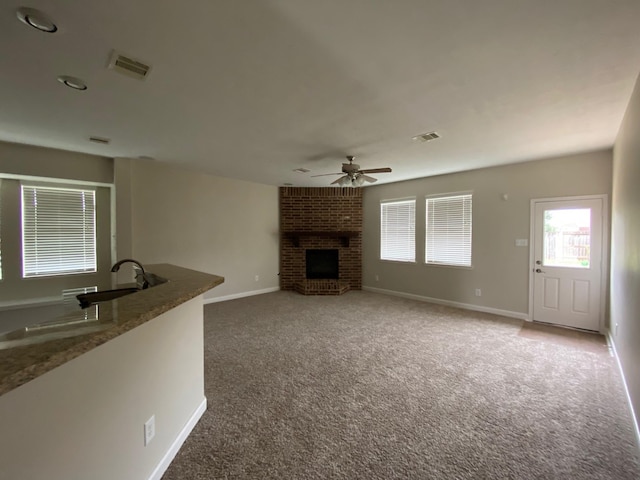 3603 Morgans Cove Ct, Katy, TX 77494 - unfurnished living room featuring a sink, a fireplace, a ceiling fan, carpet floors, and baseboards