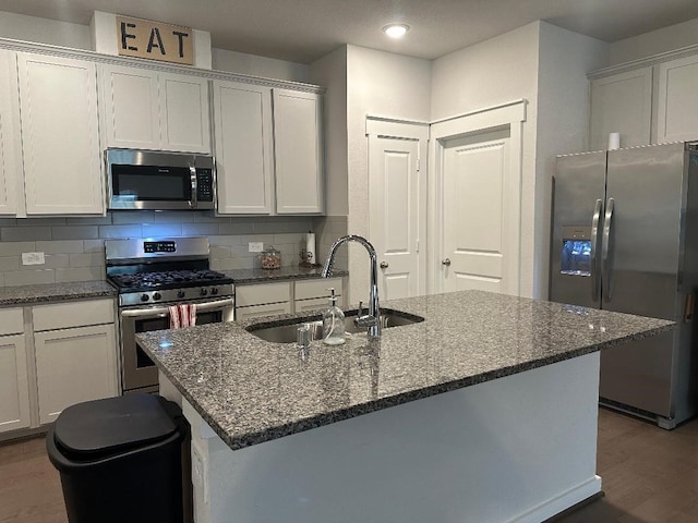 12148 Brazos Dr, Willis, TX 77378 - kitchen featuring stainless steel appliances, a sink, wood finished floors, dark stone countertops, and recessed lighting
