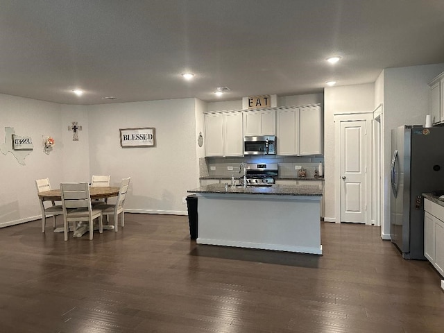12148 Brazos Dr, Willis, TX 77378 - kitchen featuring stainless steel appliances, baseboards, dark wood-type flooring, recessed lighting, and dark stone counters
