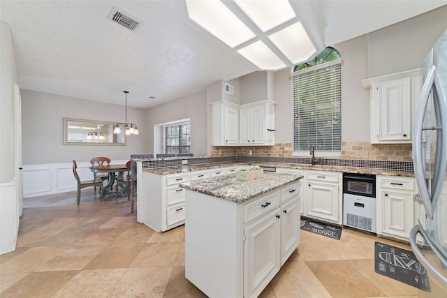 14926 Royal Birkdale St, Houston, TX 77095 - kitchen featuring a peninsula, backsplash, freestanding refrigerator, white cabinets, and wainscoting