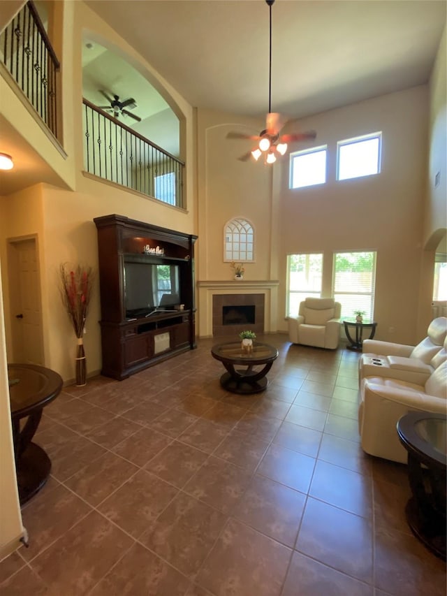 15 S Marshside Pl, Spring, TX 77389 - living area featuring a ceiling fan, a tiled fireplace, a towering ceiling, dark tile patterned flooring, and arched walkways