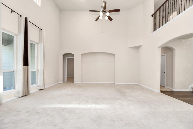 14542 Northern Mountain Ct, Houston, TX 77090 - unfurnished living room with ceiling fan, a high ceiling, arched walkways, carpet, and baseboards