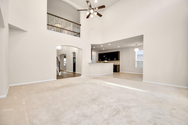 14542 Northern Mountain Ct, Houston, TX 77090 - unfurnished living room featuring arched walkways, carpet floors, a ceiling fan, baseboards, and a high ceiling