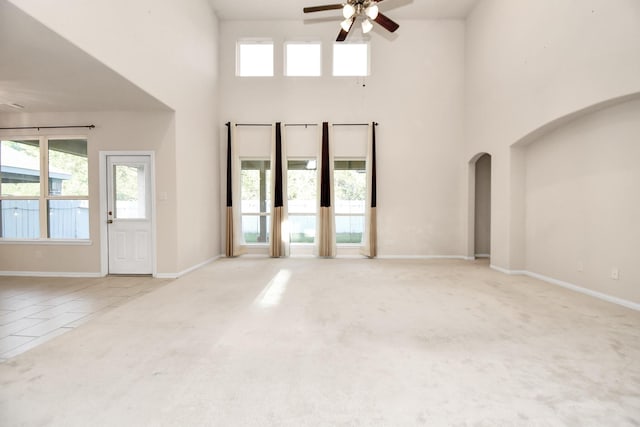 14542 Northern Mountain Ct, Houston, TX 77090 - unfurnished living room with ceiling fan, a towering ceiling, arched walkways, carpet, and baseboards