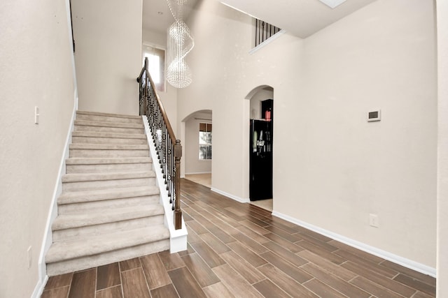 14542 Northern Mountain Ct, Houston, TX 77090 - stairs featuring arched walkways, baseboards, wood finish floors, and a towering ceiling