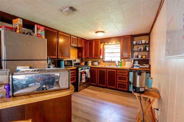 522 Price Dr, San Augustine, TX 75972 - kitchen featuring stainless steel appliances, open shelves, a sink, light wood-type flooring, and light countertops