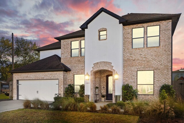 1211 Chamboard Ln, Houston, TX 77018 - french country home featuring concrete driveway, an attached garage, brick siding, and a shingled roof