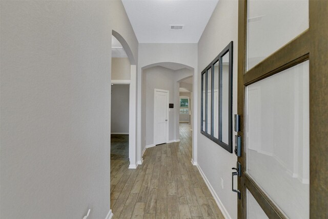 12407 Palo Acebo Ln, Humble, TX 77346 - corridor with arched walkways, light wood-style floors, and baseboards