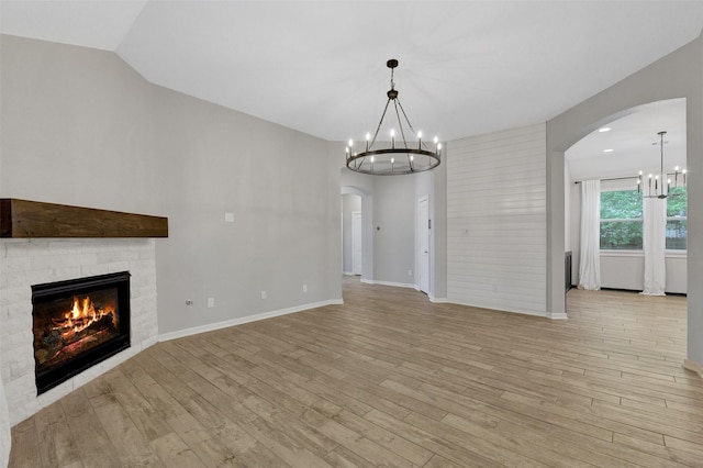 12407 Palo Acebo Ln, Humble, TX 77346 - unfurnished living room featuring a chandelier, arched walkways, a fireplace, light wood-style floors, and baseboards