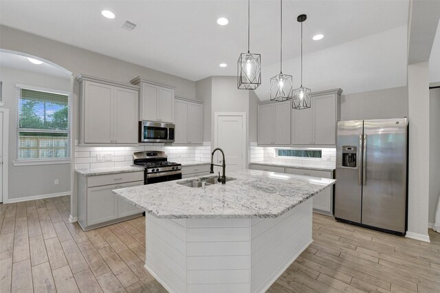 12407 Palo Acebo Ln, Humble, TX 77346 - kitchen with appliances with stainless steel finishes, a sink, arched walkways, light wood-style floors, and recessed lighting