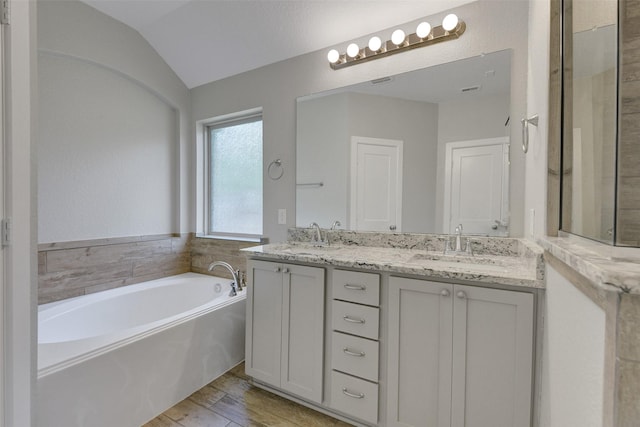 12407 Palo Acebo Ln, Humble, TX 77346 - bathroom with a bath, double vanity, lofted ceiling, and wood finished floors