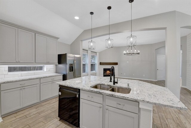 12407 Palo Acebo Ln, Humble, TX 77346 - kitchen with stainless steel fridge with ice dispenser, a sink, a lit fireplace, black dishwasher, and light wood finished floors