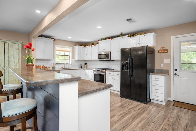 416 State Highway 21 E, Crockett, TX 75835 - kitchen with appliances with stainless steel finishes, a peninsula, a kitchen breakfast bar, white cabinets, and decorative backsplash