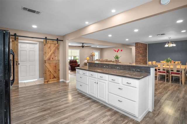 416 State Highway 21 E, Crockett, TX 75835 - kitchen featuring a barn door, light wood-style flooring, white cabinets, freestanding refrigerator, and open floor plan