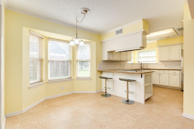 333 Banyan Dr, Lake Jackson, TX 77566 - kitchen with backsplash, a kitchen breakfast bar, ornamental molding, decorative light fixtures, and a peninsula