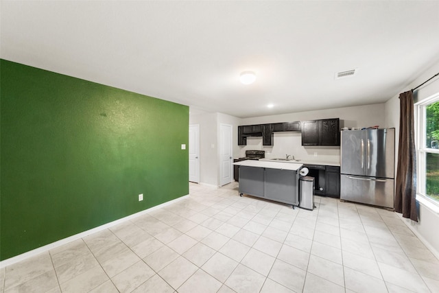 15229 Travis Ln, Willis, TX 77378 - kitchen with freestanding refrigerator, a sink, a center island, light countertops, and baseboards