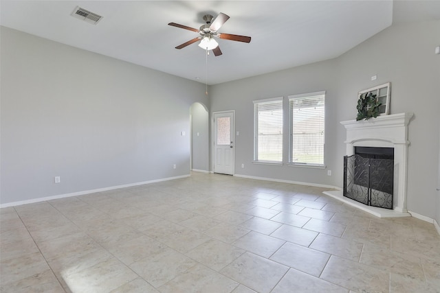 10014 Mahaffey Rd, Tomball, TX 77375 - unfurnished living room with arched walkways, ceiling fan, a fireplace with raised hearth, light tile patterned floors, and baseboards