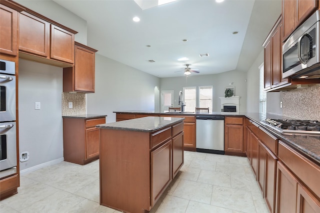 10014 Mahaffey Rd, Tomball, TX 77375 - kitchen featuring stainless steel appliances, a peninsula, a sink, backsplash, and a ceiling fan