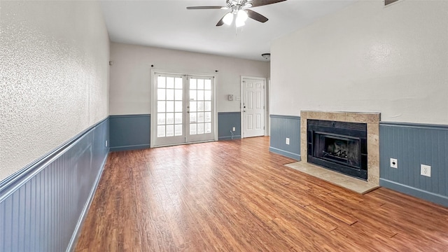 2121 El Paseo St Unit 1511, Houston, TX 77054 - unfurnished living room with ceiling fan, a wainscoted wall, wood finished floors, a fireplace, and french doors