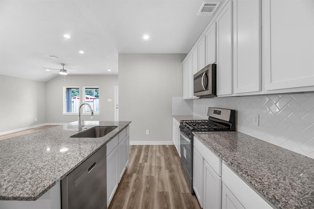 311 Emma St, Angleton, TX 77515 - kitchen with stainless steel appliances, a sink, light wood finished floors, decorative backsplash, and white cabinets