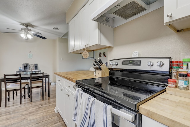 kitchen with stainless steel electric stove, butcher block countertops, under cabinet range hood, and white cabinets