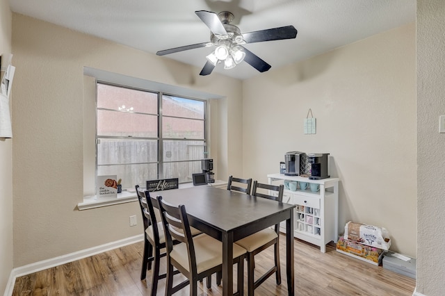 dining space featuring light wood finished floors, a ceiling fan, and baseboards