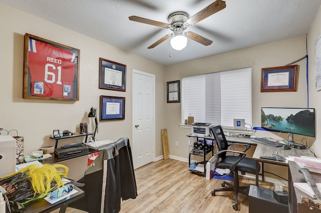 office space with a ceiling fan, light wood-style flooring, a textured ceiling, and baseboards