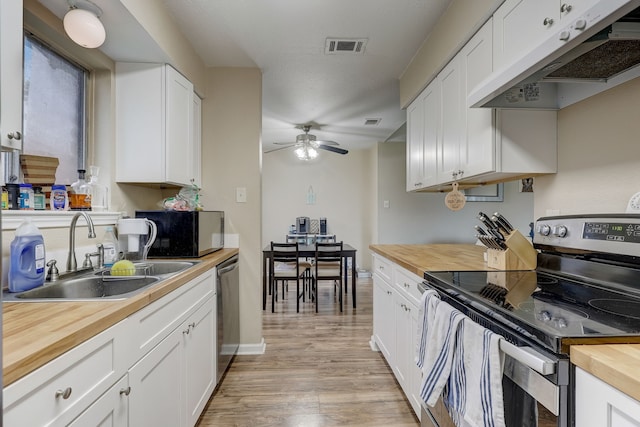 kitchen with wood counters, appliances with stainless steel finishes, under cabinet range hood, a sink, and ceiling fan