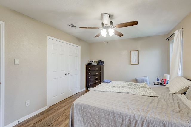 bedroom with wood finished floors, baseboards, a closet, and ceiling fan