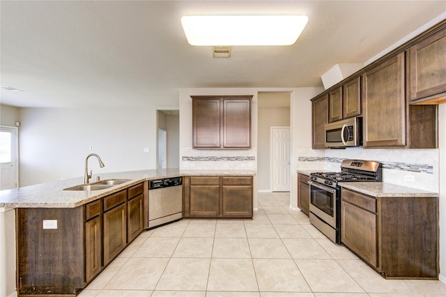 2831 Lake Villa Dr, Missouri City, TX 77459 - kitchen featuring stainless steel appliances, a sink, decorative backsplash, light tile patterned floors, and light stone countertops