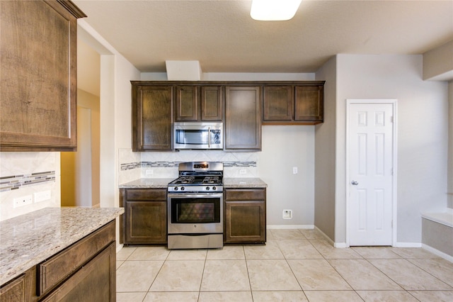 2831 Lake Villa Dr, Missouri City, TX 77459 - kitchen featuring appliances with stainless steel finishes, tasteful backsplash, light stone countertops, light tile patterned floors, and dark brown cabinetry