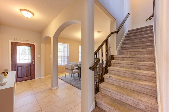2831 Lake Villa Dr, Missouri City, TX 77459 - foyer entrance with arched walkways, stairs, light tile patterned floors, and baseboards